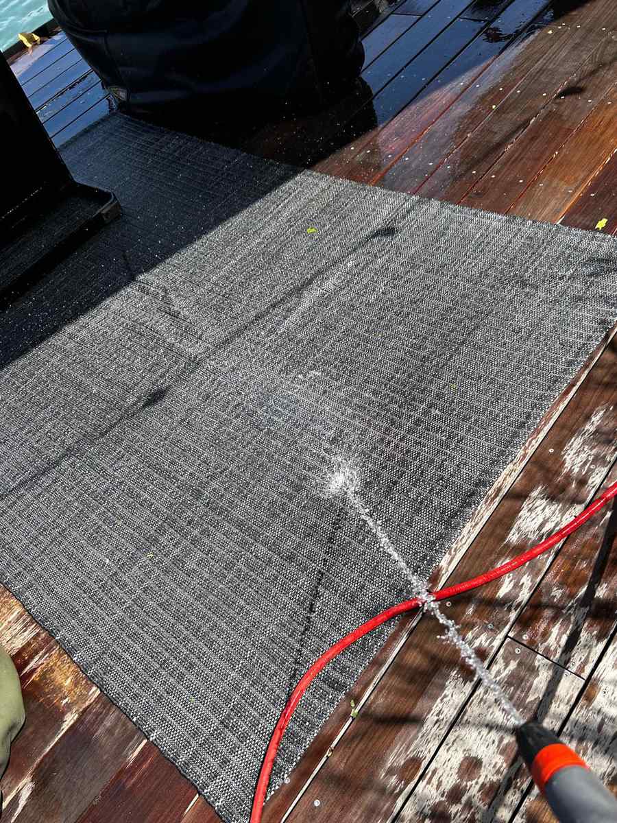 Tapis extérieur rincé au tuyau sur une terrasse en bois mouillée