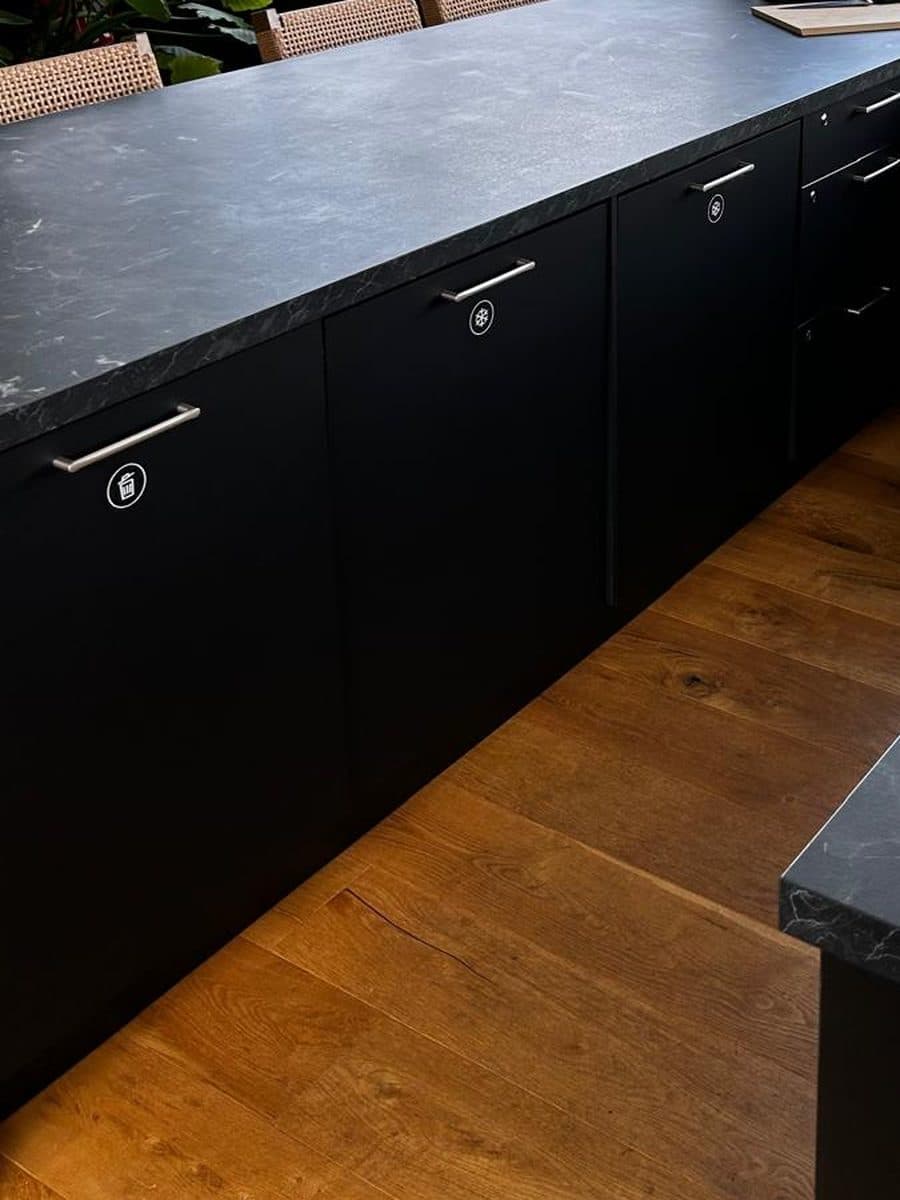 Cuisine noire en U avec suspensions en rotin, parquet chêne