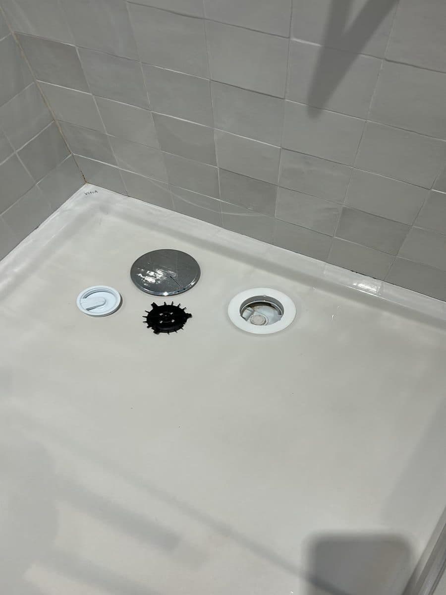 Siphon de douche démonté, pièces posées sur le receveur