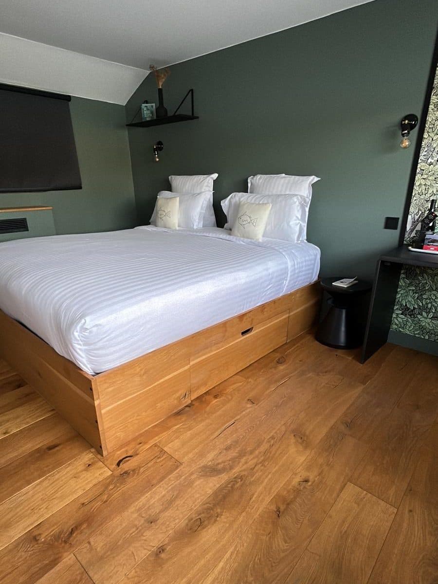 Chambre au mur vert de gris, lit fait de linge blanc