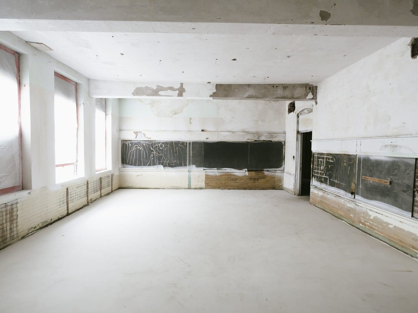 Pièce en travaux aux murs partiellement refaits, grandes fenêtres